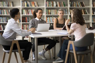 Üniversite kampüsünde birlikte okuyan çeşitli yeni öğrencilerden oluşan bir grup, kütüphanede masada oturup konuşuyorlar, eğitimi tartışıyorlar, sınıf projelerini tartışıyorlar, çok ırklı bir takımda ev ödevi yapıyorlar.