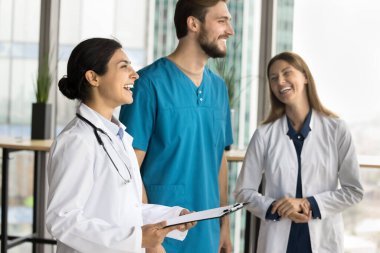 Genç Hintli pratisyen kadın klinikteki meslektaşlarıyla buluşurken eğleniyor. Muhtelif doktorlar hastane koridorunda duruyor, konuşuyor, tıbbi iş başarısını tartışıyorlar.