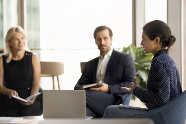 Ciddi Hintli genç iş kadını takımla toplantıda konuşuyor, görevlerin tamamlanması, proje planı, ofis iş arkadaşlarıyla konuşma gibi yaratıcı fikirleri anlatıyor.