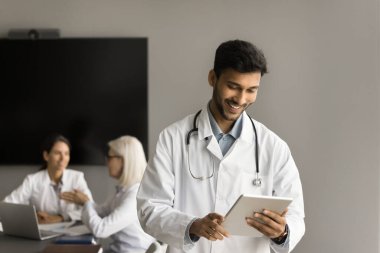 Mutlu, çekici Hintli doktor internet sağlık hizmetlerini iletişim kurmak için tablet üzerinde kullanıyor. Sınav elektronik sonuçlarını okuyor, iş için online içerik, gülümseme.