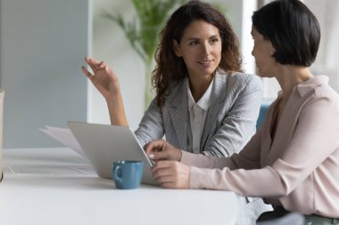 Dizüstü bilgisayarla konuşan, online proje, iş stratejisi, plan, fikir sunan, beyin fırtınası yapan farklı yaştaki iş arkadaşlarıyla meşgul. Genç iş kadını kıdemli meslektaşımla konuşuyor.