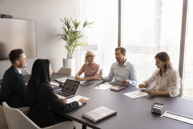 Erkek işletme koçu çeşitli çalışanları eğitiyor. Erkek patron iş arkadaşlarıyla konuşuyor, toplantı masasında konuşuyor, talimatları açıklıyor, çalışanları motive ediyor.