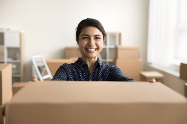 Neşeli, genç, Hintli bir web mağazası çalışanı paket veriyor, karton kutu gösteriyor, kameraya bakıyor, ulaşım için konteynır hazırlıyor, internet mağazası dağıtımını destekliyor.
