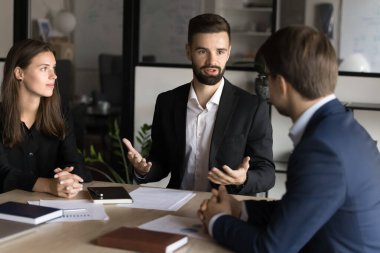 Ciddi genç patron toplantı masasında proje yöneticileriyle konuşuyor. Takım çalışması için motive eden iş lideri, iş verenler, talimatlar, iş arkadaşlarıyla proje üzerinde beyin fırtınası yapan