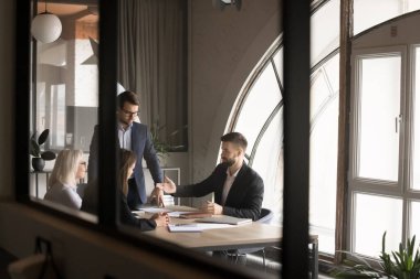 İş arkadaşları ve liderlerden oluşan bir ekip masada konuşuyor. Çağdaş ofiste cam duvarlarla beyin fırtınası yapıyorlar. Modern toplantı odasının içindeki iş projelerini tartışıyorlar. Gizli çekim.