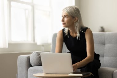 Ev bilgisayarında çalışan, daktilo eden, başka yere bakan, proje üzerinde düşünen, problem çözen, karar veren, çevrimiçi iletişim teknolojisini kullanan düşünceli, olgun bir iş kadını.