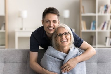 Yakışıklı, sevecen, yetişkin bir oğul. Mutlu, olgun bir anneye arkadan sarılıyor. Annesinin omzunu ekose kumaşla sarıyor, rahat bir örtü takıyor.