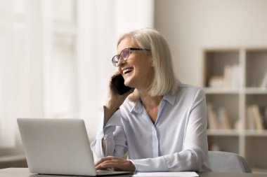 Cep telefonuyla konuşan, cep telefonuyla konuşan, cep telefonuyla konuşan, gülen, başka yöne bakan, kablosuz bağlantıyı iş bağlantısı olarak kullanan başarılı, başarılı, yaşlı iş kadını.