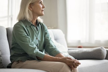 Bunalıma girmiş yaşlı bir kadın stresli, stresli problemler yaşıyor, kötü haberler, evde kanepede oturuyor, üzgün, endişeli, endişeli, endişeli, derin düşüncelerde ağlamak üzere.