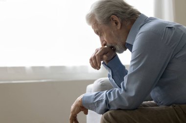 Depresyondaki yaşlı adam, evde oturuyor, aşağı bakıyor, emekliliği düşünüyor, sağlık sorunları, depresyon, yalnız hissediyor, endişeli, ilgisizlik, endişe, yalnızlık
