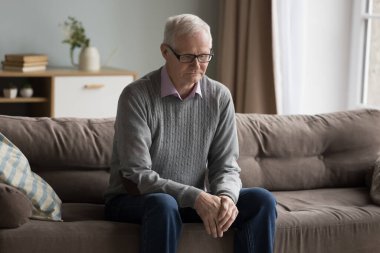 Üzgün yaşlı bir adam kendini kaybolmuş, evde yalnız hissediyor, zihinsel Alzheimer hastası, hafıza kaybı, evdeki koltukta oturup kötü düşüncelerle boşluğa bakıyor, sorunları düşünüyor.