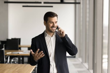 Başarılı pozitif yönetici cep telefonuyla iş projesini tartışıyor, ofisten telefon görüşmesi yapıyor, cep telefonuyla konuşuyor, gülümsüyor, gülüyor, iş iletişimi için cep telefonu kullanıyor.