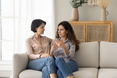 Farklı yaşlarda çekici kadınlar, olgun anne ve genç yetişkin kız koltukta oturup güvenilir konuşmalar yapıyorlar, kişisel haberleri veriyorlar, sorunları anlatıyorlar, destek alıyorlar, tavsiye istiyorlar, hayattaki sorunları evlerinde paylaşıyorlar.