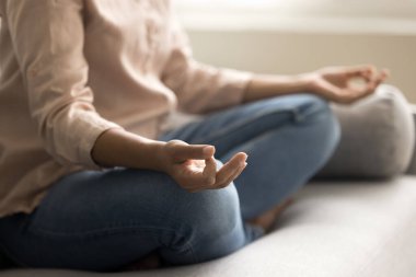 Zen hands on knees of young yogi woman meditating on sofa, doing breathwork, working on concentration, mindfulness in lotus pose at home, practicing meditation, focus, mindfulness clipart