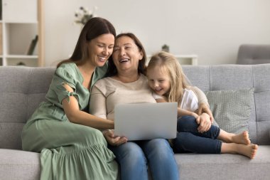 Neşeli anne, büyükanne ve çocuk dizüstü bilgisayarı birlikte kullanıyor, eğleniyor, gülüyor, eğleniyor, eğleniyor, internet teknolojisi, internet iletişimi, evdeki dijital eğlence