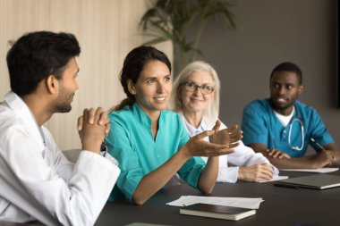 Profesyonel toplantıda çok ırklı iş arkadaşlarıyla konuşan genç, pozitif Latin cerrah kadın işbirliği ve beyin fırtınası fikirleri sunuyor. Muhtelif pratisyenler doktor mesleğini tartışıyor