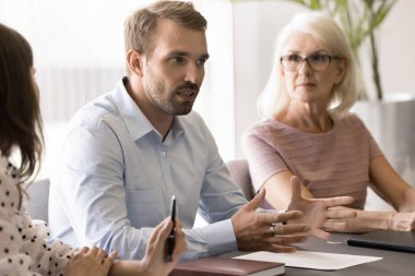 Meşgul proje yöneticisi iş arkadaşlarıyla beyin fırtınası yapma fikirleri sunuyor, konferans masasında farklı yaşlardaki iş arkadaşlarıyla konuşuyor, yönetim stratejisini tartışıyor.