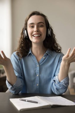 Çevrimiçi neşeli zombi öğrenci kulaklıklı kız. Telif defterinde yazılı notlarla konuşuyor. Gülümsüyor, gülüyor, kameraya konuşuyor. Video ekranı, dikey kafa resmi portresi