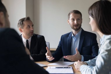 Kendine güveni tam, hırslı, takım elbiseli genç bir iş adamı. Proje sunumu, ortaklar, kurumsal toplantı yatırımcıları, el hareketleriyle konuşma.