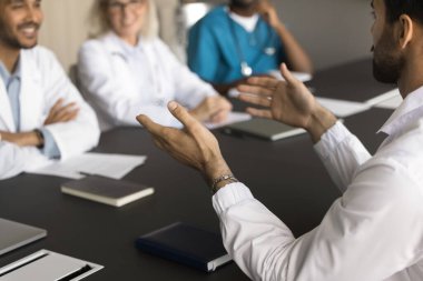 Genç erkek doktor, çeşitli olumlu meslektaşlarla konuşuyor. İşbirliği için toplanan tıp pratisyenleri, başarılı iş davalarını, konferans masasında sağlık sorunlarını tartıştılar