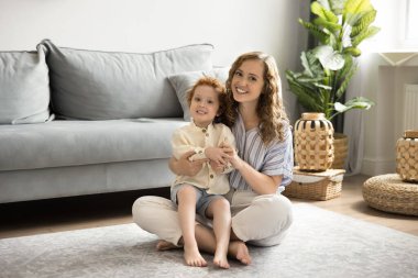Mutlu, sevgi dolu bir anne kucağında neşeli bir çocuk, evde oturmuş, anneliğin tadını çıkarıyor, çocuk bakıcılığı yapıyor, oğlanla oyun oynuyor, kameraya bakıyor, gülümsüyor, gülüyor.