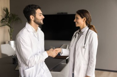 İki pozitif doktor klinikte el sıkışıyor, toplantı salonunda buluşuyor, konuşuyor, sağlık hizmetleri mesleğini tartışıyorlar. Kendine güvenen erkek doktor, bayan meslektaşıyla tokalaşıyor.