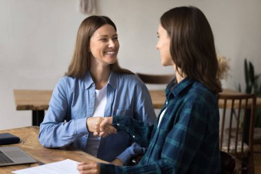 İki neşeli genç ortak el sıkışıyor, görüşmeleri tamamlıyor, anlaşma sağlanıyor. Günlük gömlekler içinde mutlu genç kadınlar çalışma masasında tokalaşıyor, gülümsüyor, gülüyorlar.