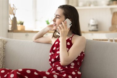 Güzel bir genç kadın cep telefonuyla konuşuyor, telefonla konuşuyor, gülüyor, cep telefonuyla arkadaşlarıyla konuşuyor, kanepede dinleniyor, başka yere bakıyor, düşünüyor, dinliyor.