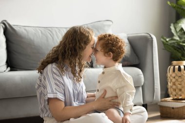 Neşeli, genç bir anne çocuk bakımı, annelik, kucağında küçük bir çocukla kucağında kucağında kucağında kucağında kucağında kucağında küçük bir çocuk, yüzünde burun dokunuşları, gülümseyen bir çocuk.