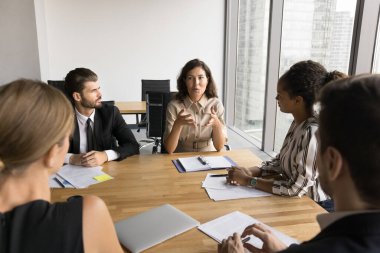 Orta yaşlı iş adamları proje yönetimi ve iş stratejisi için fikirler sunuyor. Genç Afrikalı kadın patronla çeşitli takımlar başlangıç aşamasında beyin fırtınası yapıyor, büyük masada toplanıyorlar.