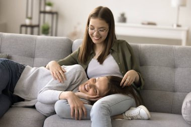 Olumlu genç kız mutlu anneye sevgiyle, özenle sarılıyor, gülüyor. Genç bir anne yakın ilişkilerde eğleniyor, ergen bir çocukla arkadaşlık kuruyor, çocuklu bir kanepede dinleniyor, konuşuyor.