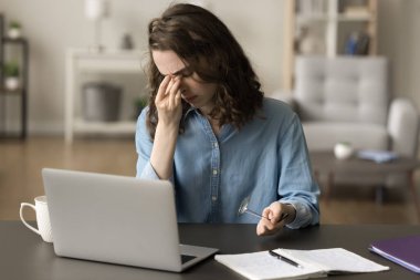 Dizüstü bilgisayarda çalışan, gözlük takan, kapalı gözlere dokunan, göz kapaklarını, burnunu, yüzünü ovuşturan, görme güçlüğü çeken, kaşınan gözlerden muzdarip, baş ağrısı olan bıkkın, serbest çalışan bir kız.