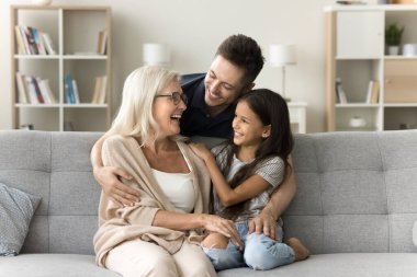 Neşeli, şefkatli, yakışıklı baba büyükannesine ve kızına sevgiyle sarılıyor, kanepenin arkasından şefkat gösteriyor. Torun, büyükanne ve yetişkin oğul aile ilişkisinin tadını çıkarıyor, konuşuyor, gülüyor.