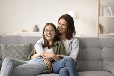 Mutlu anne ve genç kız evlerinde rahat bir portre çiziyorlar. Anne ve genç kız kanepede dinleniyorlar, sarılıyorlar, güvenle konuşuyorlar, eğleniyorlar, gülüyorlar, eğleniyorlar, bağ kuruyorlar, ilişki kuruyorlar.