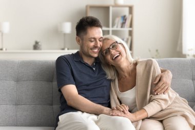 Neşeli, olgun anne ve yetişkin çocuk adam koltukta birlikte oturur, sıcakkanlılıkla, şefkatle, sevgiyle, sevgiyle, gülerek, konuşarak, aile toplantısından zevk alarak, arkadaşlıkla, iyi bir ilişkiyle, annelikle kucaklaşır.