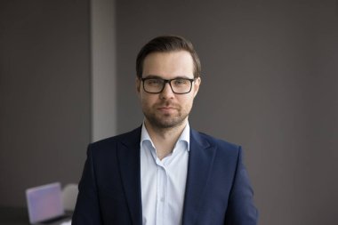 Kendine güvenen yakışıklı iş adamı resmi kıyafetler ve gözlüklerle kameraya bakıyor, gülümsüyor, gülüyor. Başarılı yönetici, yönetmen, CEO, şirket sahibi vesikalık portresi