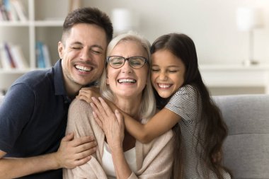 Üç mutlu aile nesli evde tanışmaktan zevk alıyor. Sevgi ve sevgiyle kucaklaşıyorlar. Sevgi dolu bir torun çocuğu ve genç bir baba. Kapalı gözlerle büyükanneyi kucaklıyor.