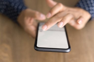 Masa yüzeyindeki kadın ellerindeki cep telefonu ekranı. Genç iş kadını akıllı telefon ekranına dokunuyor, online uygulama, servis, internet iletişimi için dijital cihaz kullanıyor. Kapat.