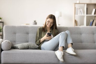 Gözlüklü genç kız internette geziniyor, cep telefonuyla sosyal medya ağı kuruyor, internetten sohbet ediyor, alışveriş yapıyor, internette sanal oyun oynuyor, boş zamanların tadını çıkarıyor, kablosuz iletişimin tadını çıkarıyor.