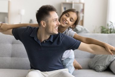 Tatlı kızım, mutlu ve şefkatli babayla uçak uçurma oyunu oynuyor, babalara sırtüstü uzanıyor, gülümsüyor, babayla konuşuyor, boş zamanların, oyun zamanlarının, çocukluğun tadını çıkarıyor.