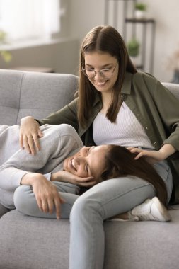 Neşeli, genç ve güzel bir kız çocuğu. Kanepede uzanmış, sevgi, özen ve kahkaha ile genç anneye sarılıyor. Genç anne ve çocuk yakın güven ilişkileri, dostluk, şefkat, boş zaman. Dikey çekim