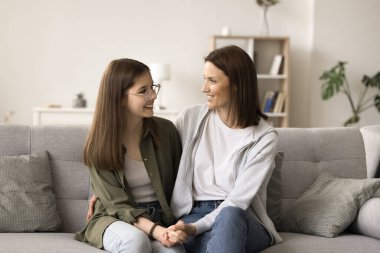 Pozitif anne ve ergen çocuk sohbet, arkadaşlık, evde vakit geçirmek, el ele tutuşmak, kanepeye yakın oturmak, konuşmak, gülümsemek, gülmek, mutlu kızların başarısını kutlamak.
