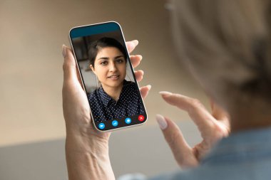 Olgun bir kadın cep telefonu tutuyor, görüntülü konuşuyor, güzel Hintli bir arkadaşla konuşuyor, müşteri destek servisi danışmanı, iş arkadaşı, ekran başındaki portreden bakıyor.