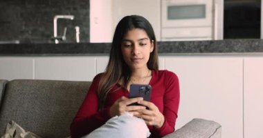 Çekici Hintli genç bir kadın cep telefonuyla hoş haberler okuyor. Mutlu hissediyor, davet alıyor, tüm biletleri satıyor, büyük indirimler yapıyor, büyük fırsatlar sunuyor, satın alıyor, satıştan zevk alıyor.