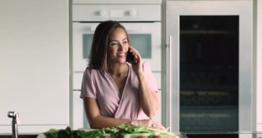 Akıllı telefonda vejetaryen yemeği pişiren güzel genç bir kadın. Gülümseyen kadınlar cep telefonlarını tutar. Çağrıya cevap verir, arkadaşlarıyla hoş sohbetler yapar, yemek sipariş ederler. Modern teknoloji, iletişim.