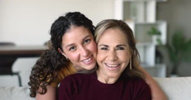 İki güzel, gülen kadın kameraya bakıyor. Çok nesilli akrabaların yakın portresi. Kadın, genç yetişkin kız, büyük annesine Cam 'e poz veriyor. Aile anları, aşk, bağlar