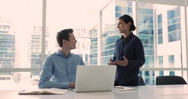 Güzel Hintli kadın akıl hocası genç beyaz erkek meslektaşına görevlerini anlatıyor, çalışıyor, konuşuyor, görüşlerini paylaşıyor, proje detayları veriyor, işbirliği planlıyor, brifinge katılıyor.