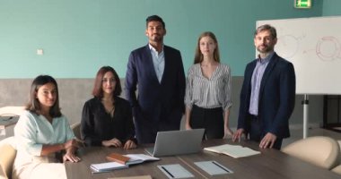 Modern ofiste kameraya poz veren beş profesyonel takım üyesi. Başarılı genç ve olgun şirket çalışanlarının portresi müzakere için hazır, seminerden ya da kurul odasında ayakta duran eğitimden sonra