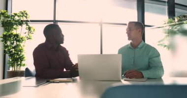 İki çok ırklı adam, takım arkadaşları, ortak görevi, modern dizüstü bilgisayarla çalışmayı, tartışmayı, yaratıcı fikirleri analiz etmeyi, başlangıç stratejisi planlamayı, takım çalışmasına bağlı arama çözümünü ele almayı düşünüyorlar.