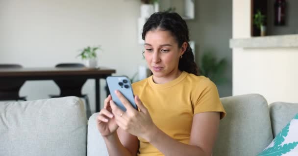 Overjoyed Latina Girl Sit Sofa Living Room Hold Smartphone Get — Stockvideo
